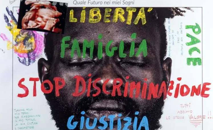 L’AQUILA: SULLE VETRINE VOLTI E SOGNI DI 26 MIGRANTI, IN CENTRO LA MOSTRA DIFFUSA PER LA PERDONANZA
